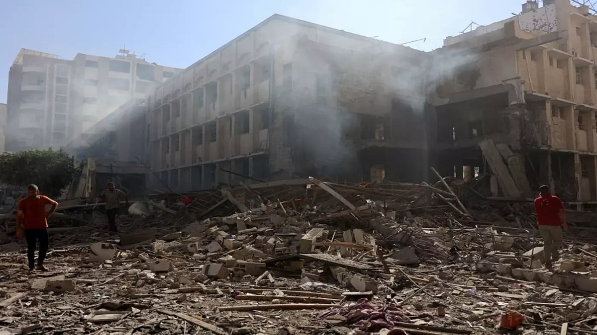 ইসরায়েলের বোমা হামলায় বিধ্বস্ত একটি স্কুলের ধ্বংসাবশেষের ওপর হাঁটছেন কয়েকজন ফিলিস্তিনি। গাজা সিটি, ৭ জুলাই, ২০২৪